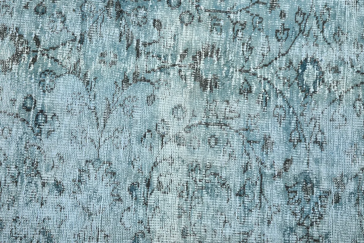 Detailed texture of the low wool pile, showing areas of natural wear and lighter blue tones.