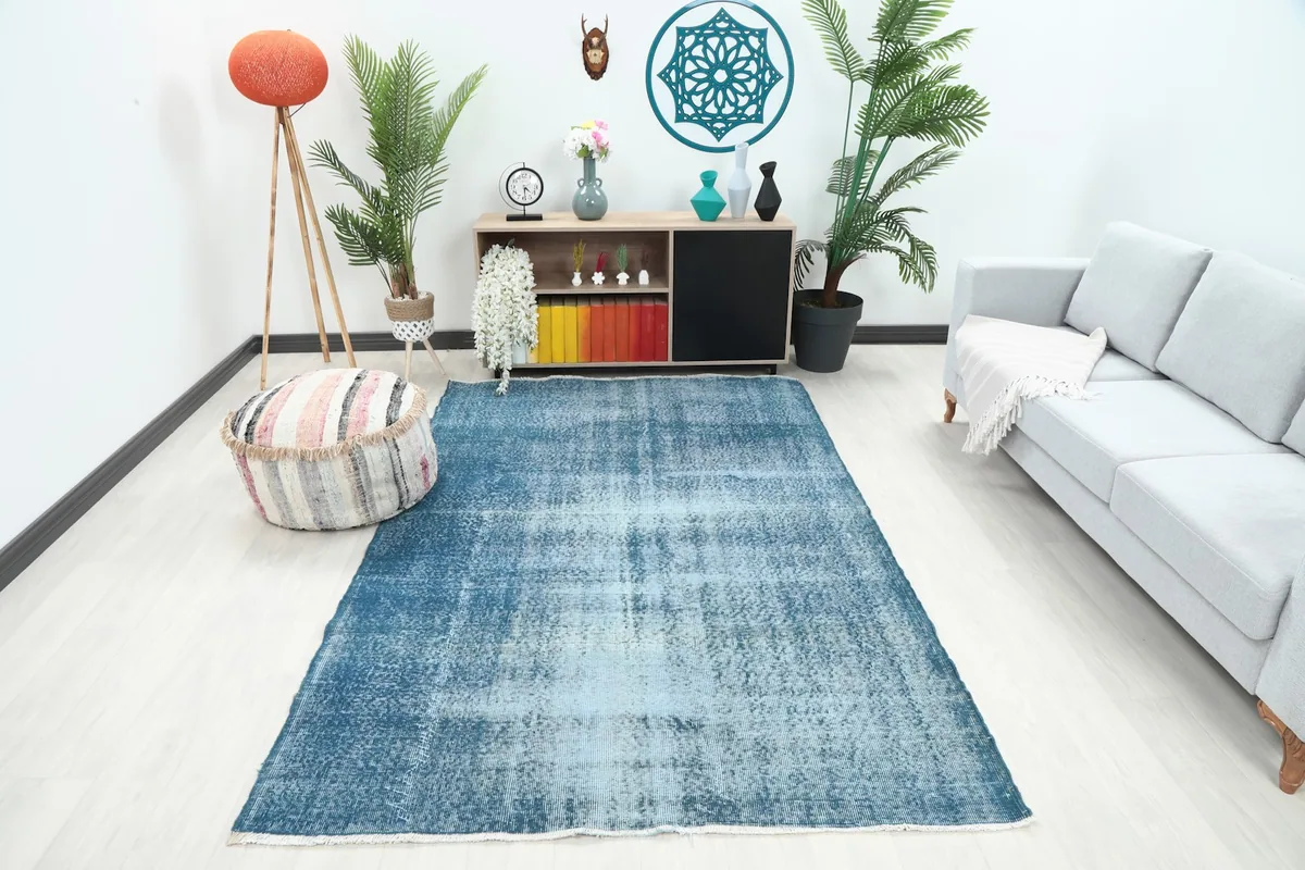 Vintage blue area rug in a modern living room setting with a light gray sofa and wooden furniture.
