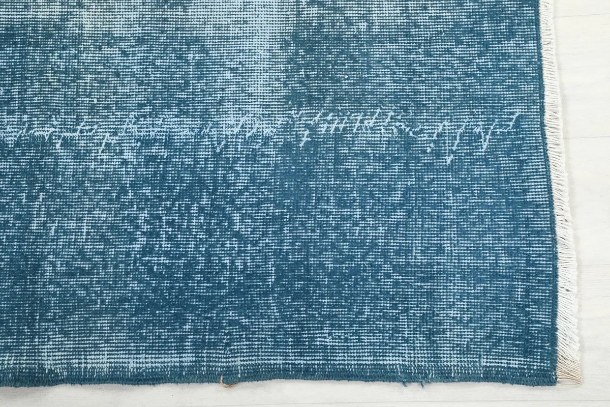 Detailed view of the distressed blue wool pile and subtle fading near the rug's edge.