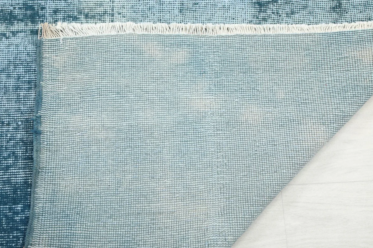 Close-up of the cotton foundation and the hand-knotted structure of the vintage rug.