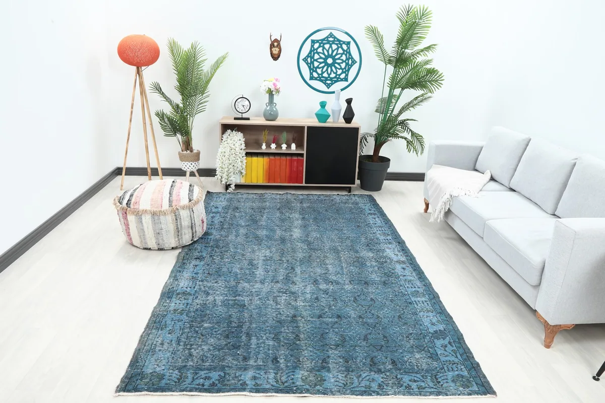 Blue area rug in a modern living room setting with a light gray sofa and ottoman