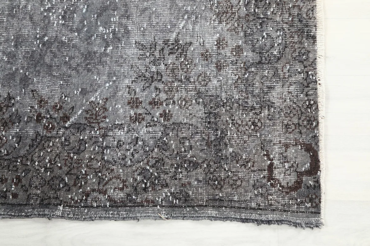 Detailed view of the rug's corner, showing the hand-knotted texture and charcoal patterns