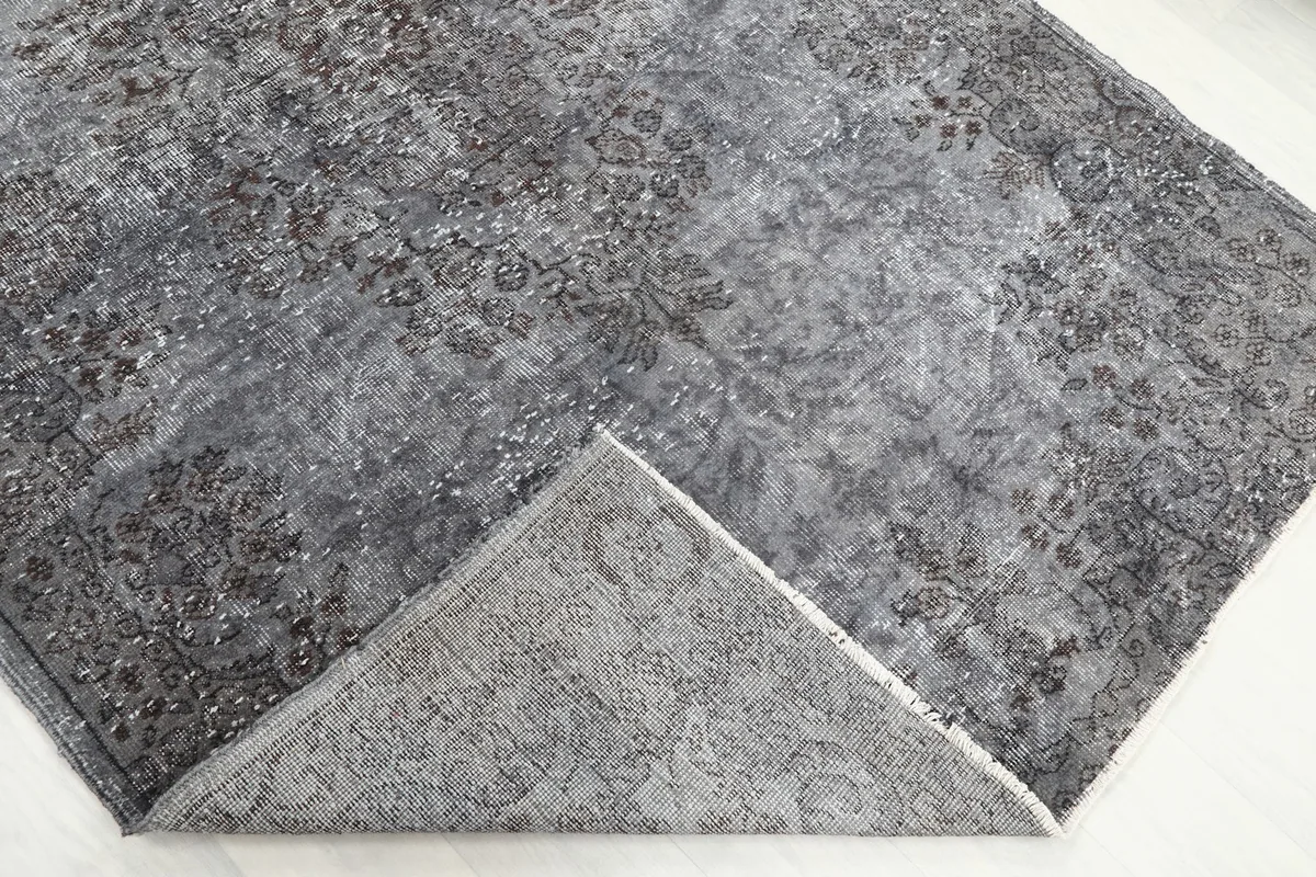 Corner of the rug folded back to reveal the cotton foundation and reverse side