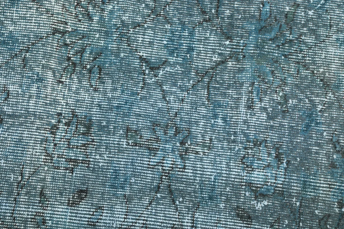 Close-up of the rug's low pile, highlighting the texture and visible wear consistent with its vintage character.