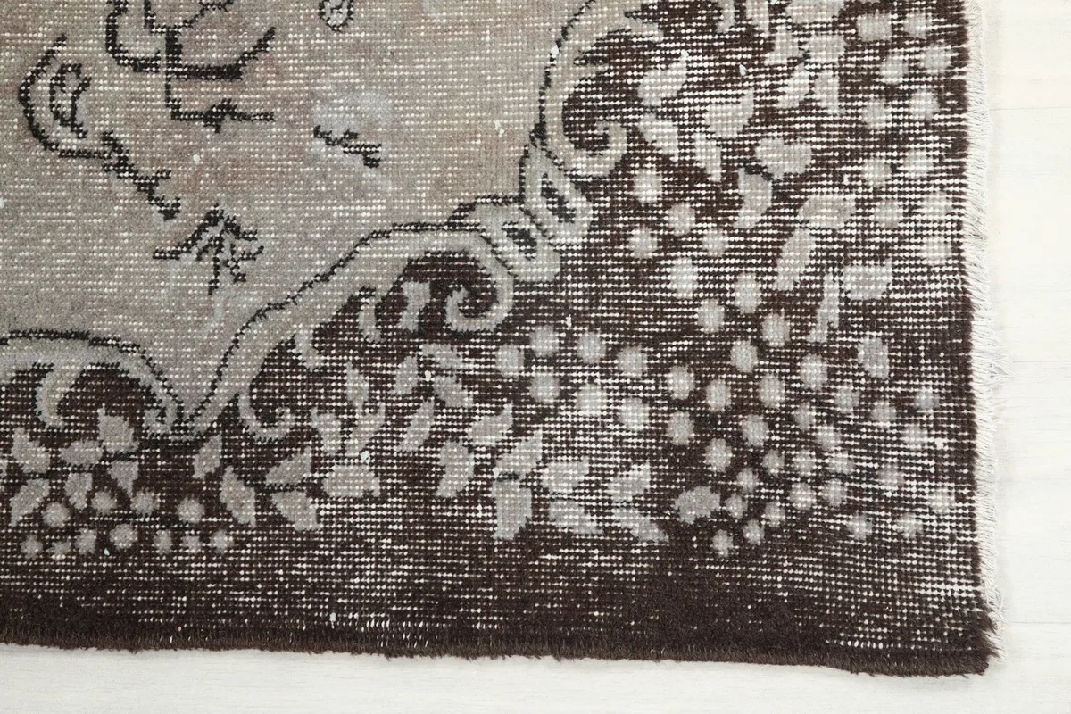 Detailed view of the brown border with white floral patterns on the vintage Anatolian rug