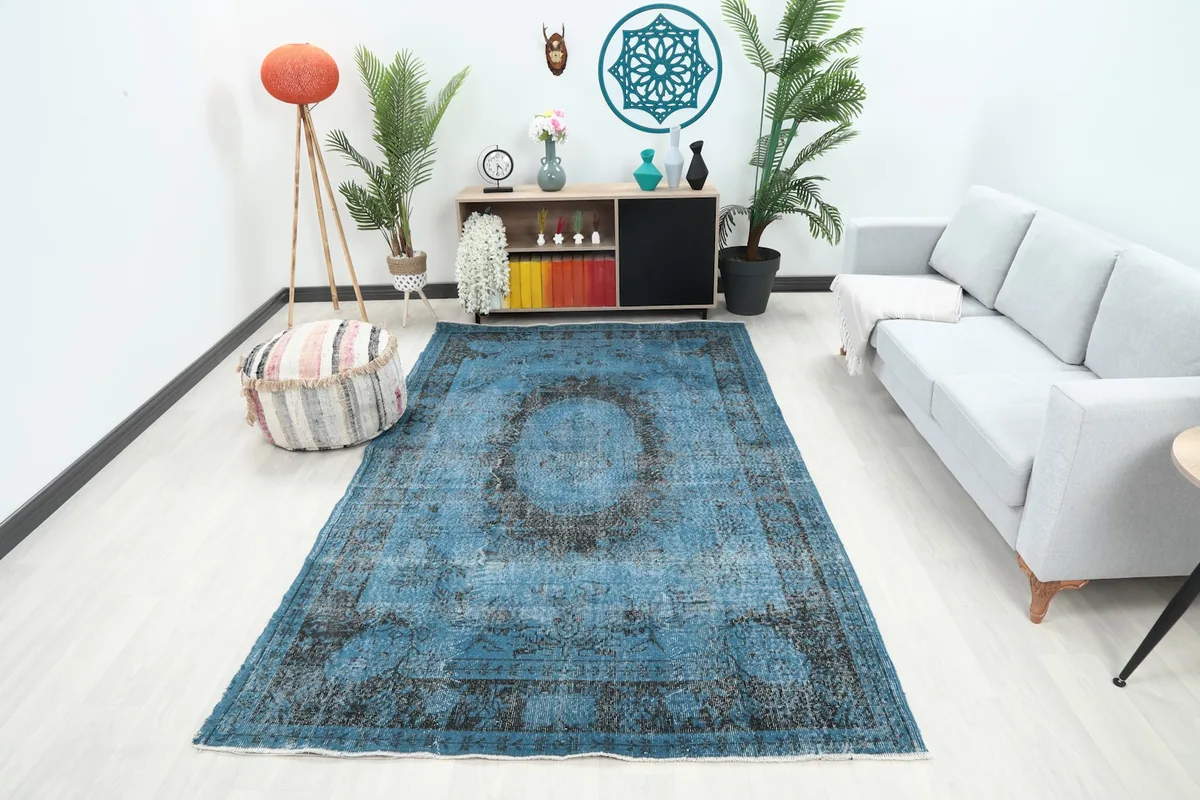 Vintage blue area rug in a modern living room setting with a sofa and pouf
