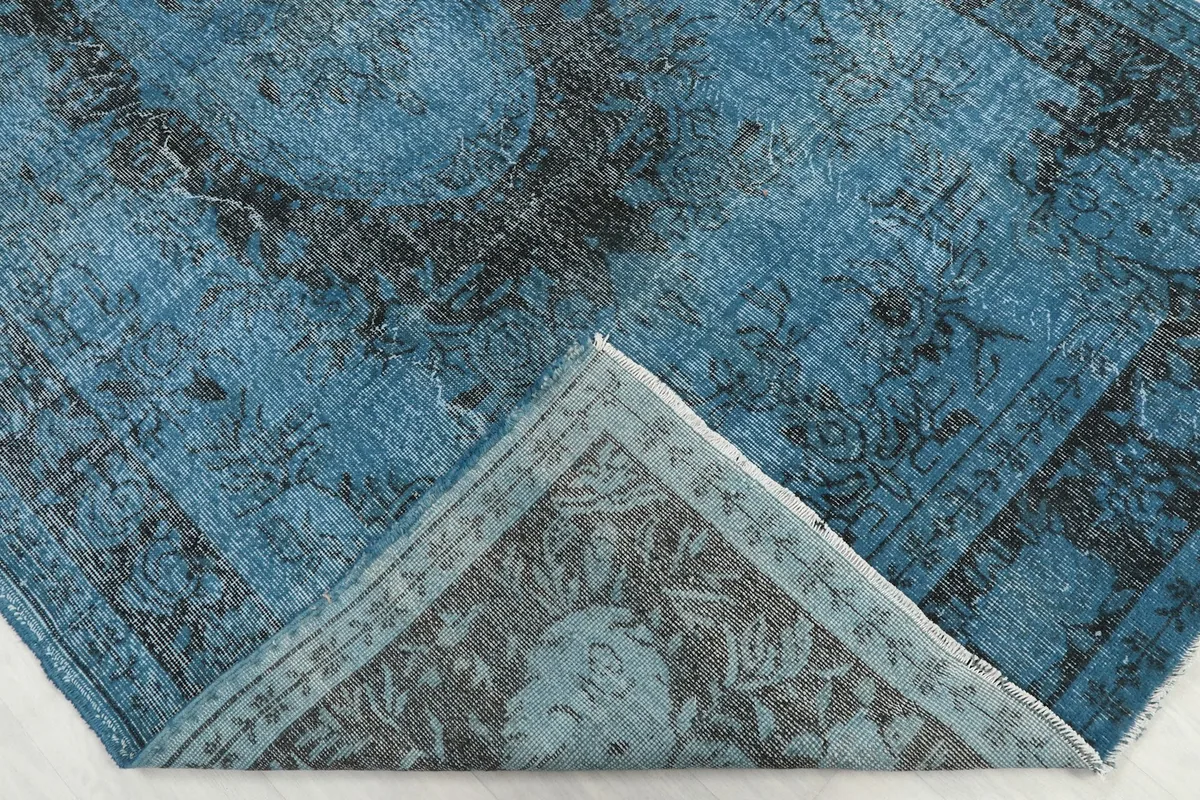 Folded corner of the rug revealing the cotton foundation and the reverse side of the hand-knotted weave