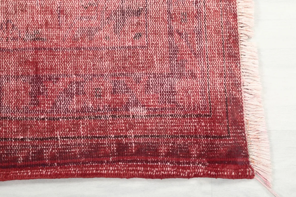 Detail of the rug's edge and fringe, showing the hand-knotted construction and color variations