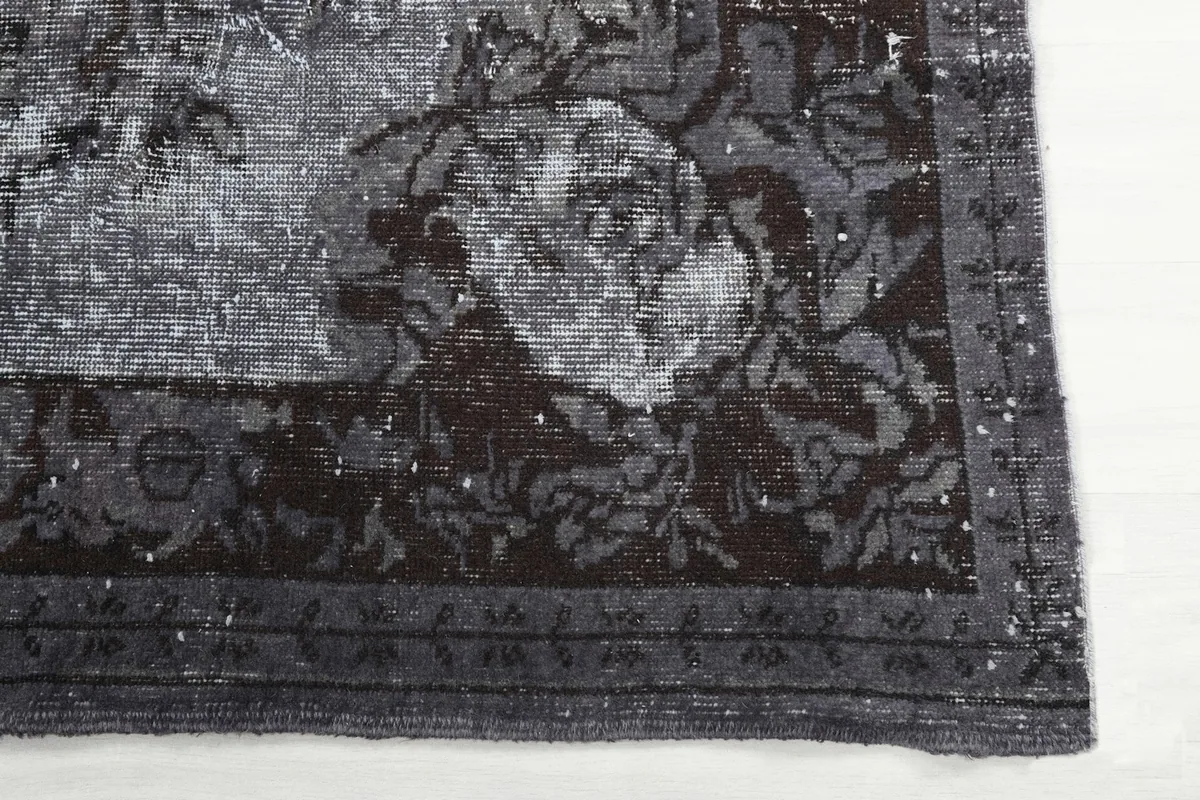 Detail of the rug's intricate brown floral border pattern and faded gray corner