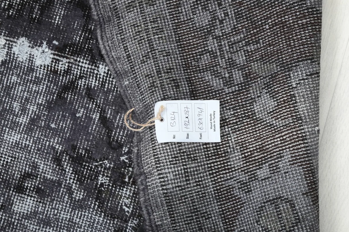 Detail of the rug's back with a product tag displaying dimensions and origin