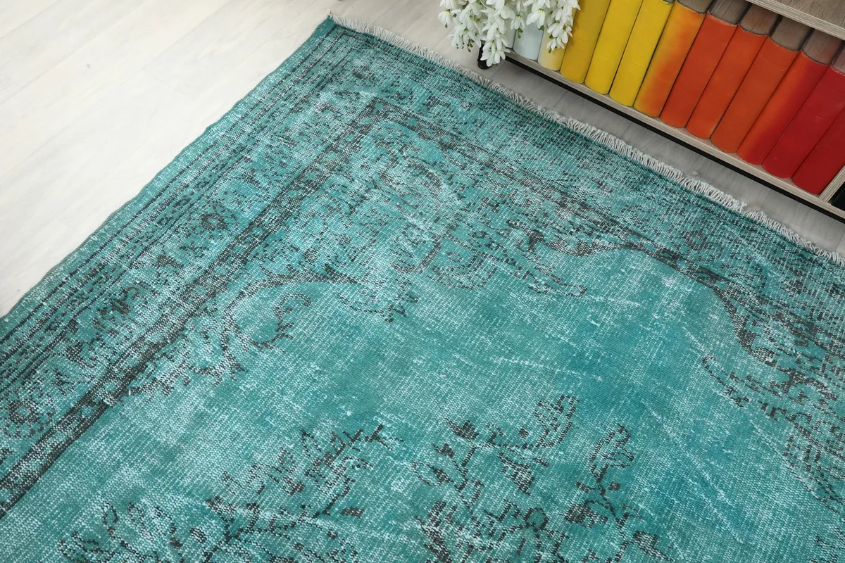 High angle view of a section of the blue and charcoal rug, with visible wear and color nuances.