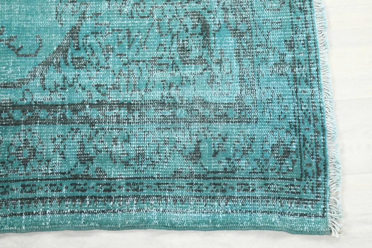 Detailed view of the rug's corner, showing the blue field, charcoal border, and subtle fringe.
