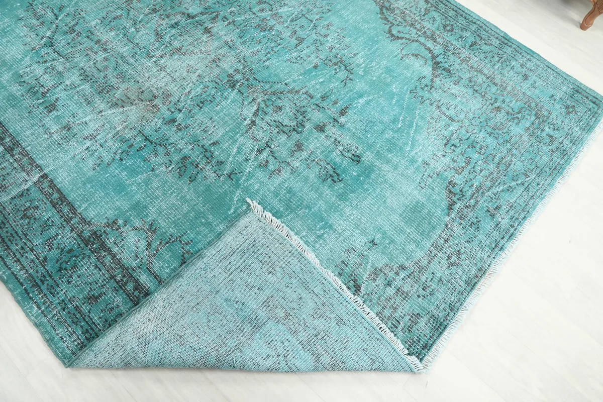 Corner of the rug folded back to show the cotton foundation and the reverse side of the hand-knotted wool.