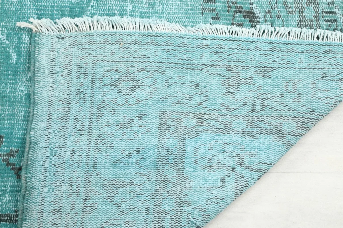 Close-up of the rug's edge, showing the short, natural cotton fringe and the tightly woven back.