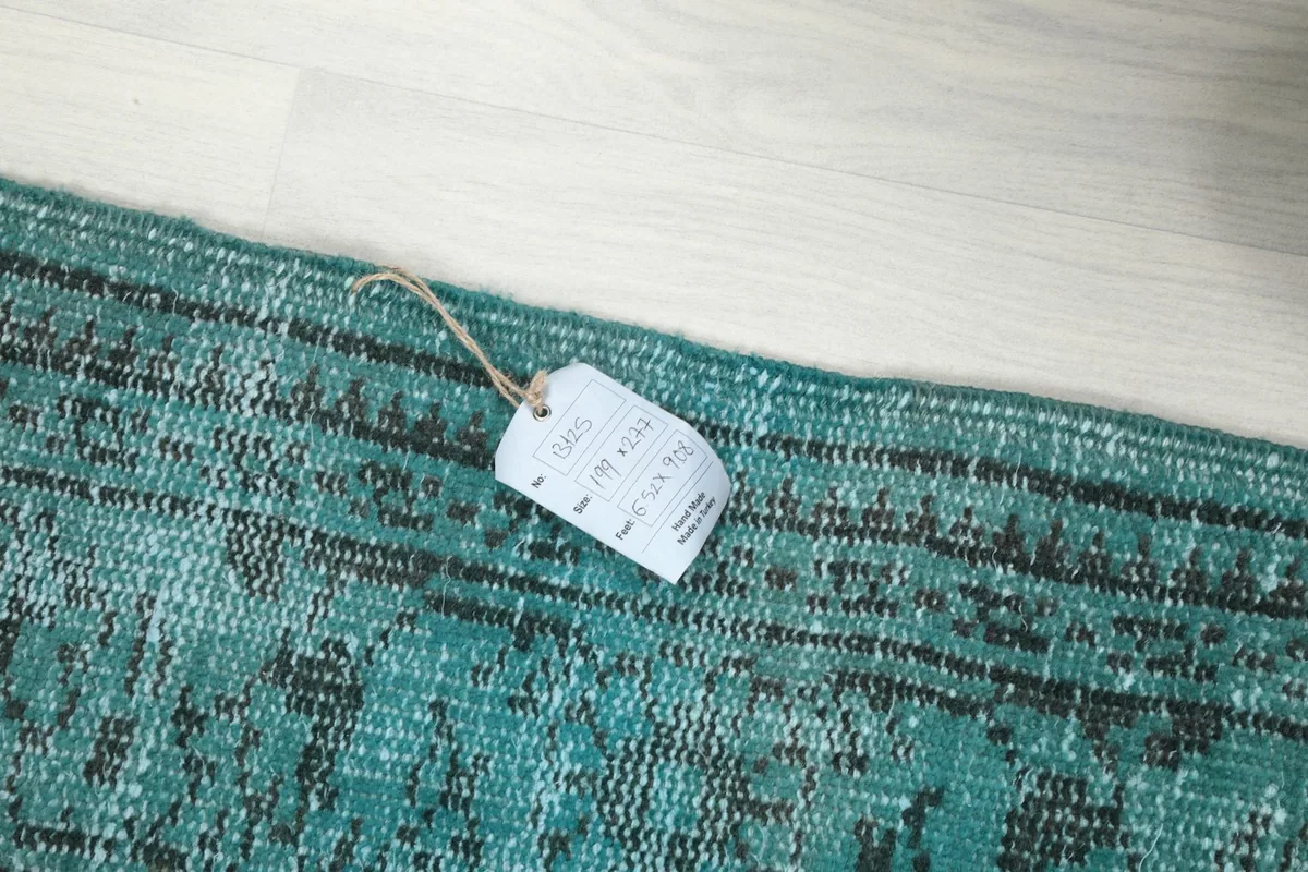 Detail of the rug's edge with the product tag, showing the size and material information.