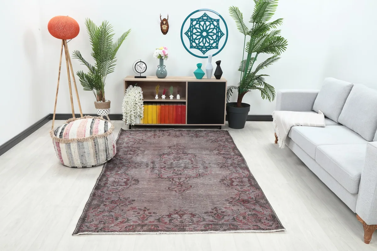 Vintage brown and rose rug placed in a modern living room setting with a light gray sofa and wooden cabinet