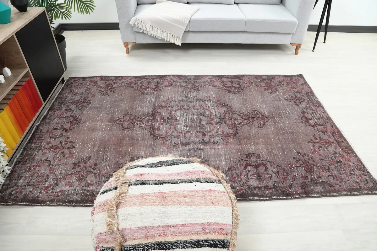 Full overhead view of the rug styled in a living room, centered with a light gray couch and ottoman
