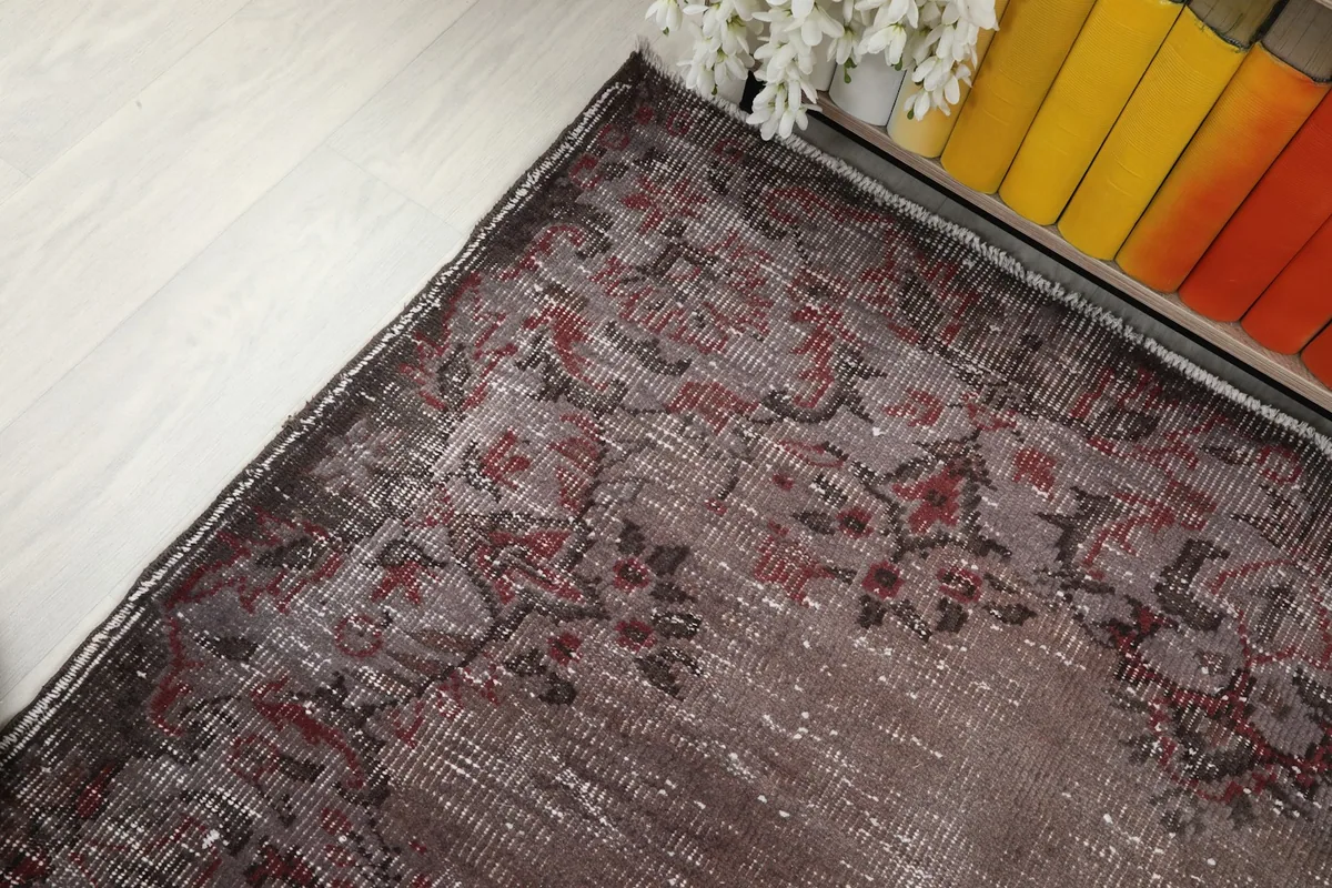 Corner detail of the rug, showing the blend of brown and rose colors with areas of natural wear