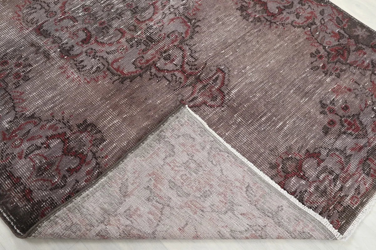 View showing a corner of the rug folded back, revealing the cotton foundation and reverse side of the knotting