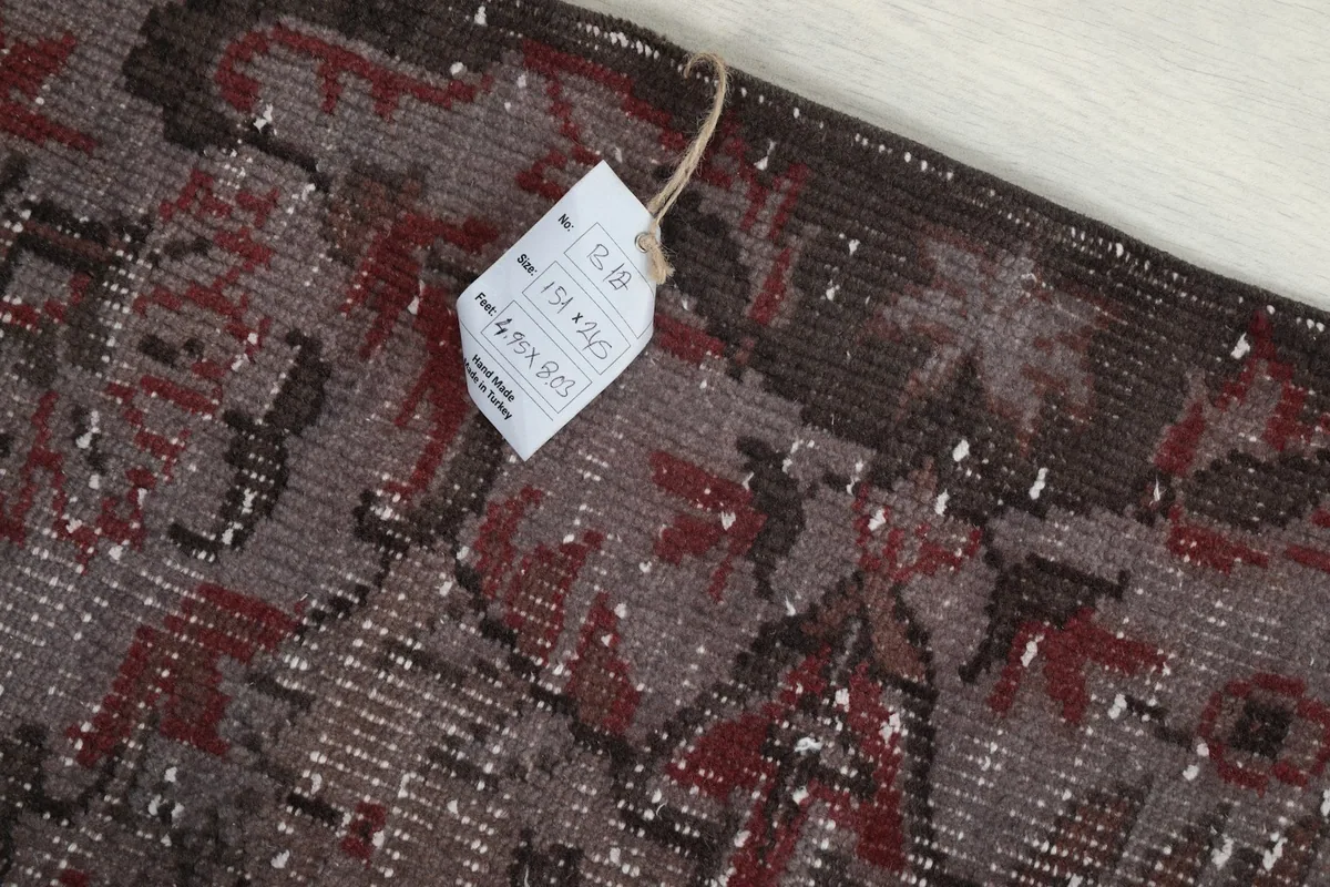 Detail shot of the rug's edge with a product tag attached, showing the texture and color of the border