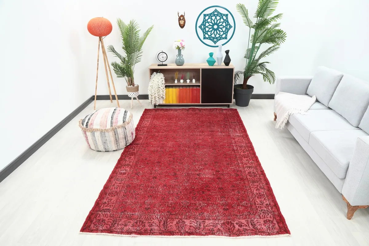 Red vintage Anatolian rug displayed in a modern living room setting with a light gray sofa.