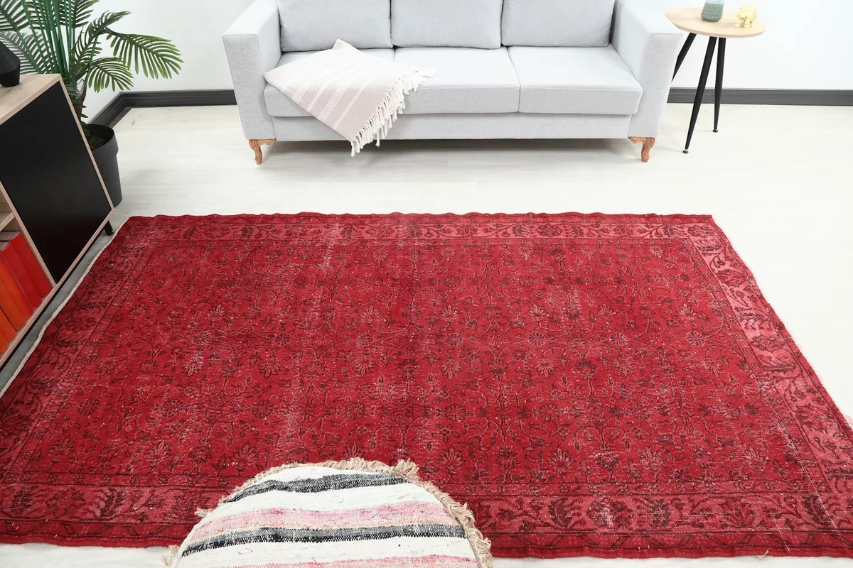 Full room view of the red rug with a sofa and ottoman, demonstrating its medium area rug size.