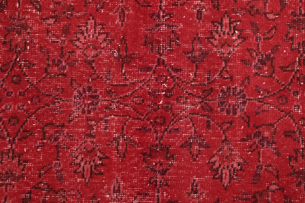 Close-up of the hand-knotted wool pile, revealing the faded red tones and intricate floral details.