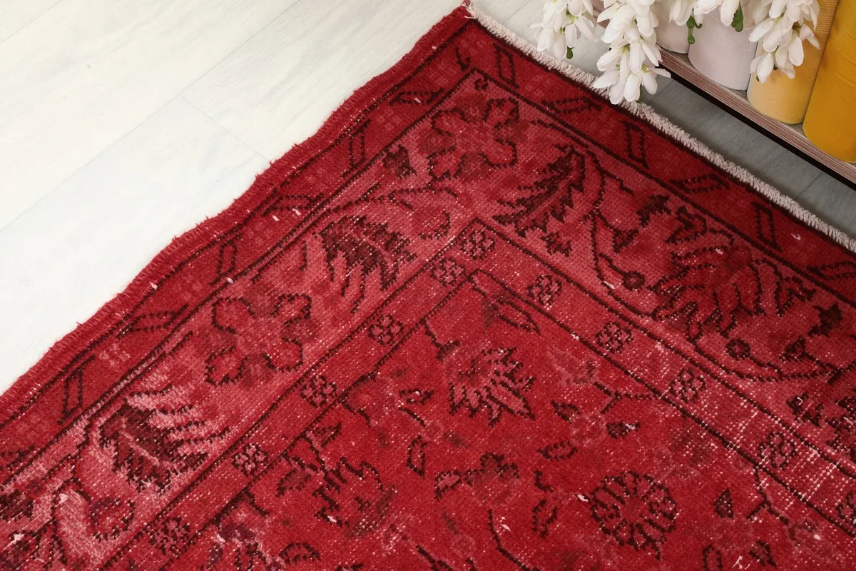 Detailed shot of the rug's border, showcasing the darker red floral design against the main field.