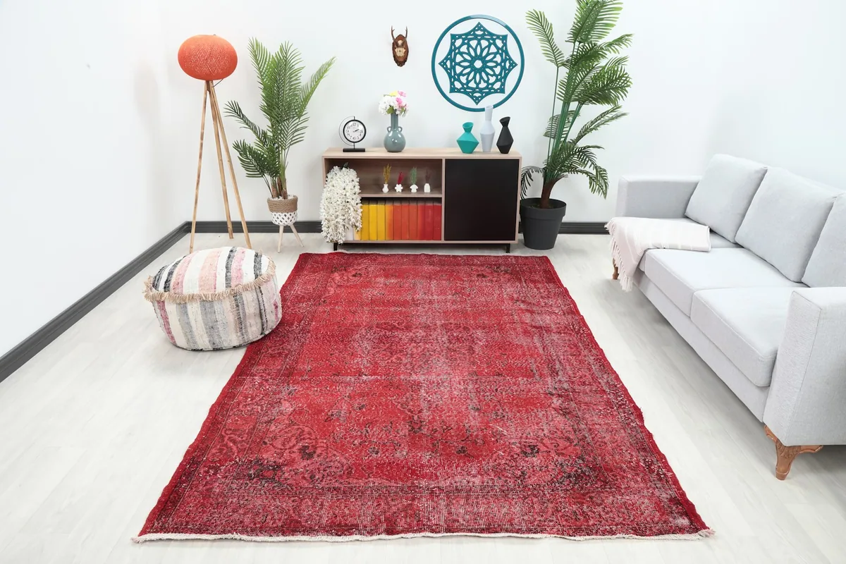 Red vintage rug placed in a living room setting, showing its scale with furniture.