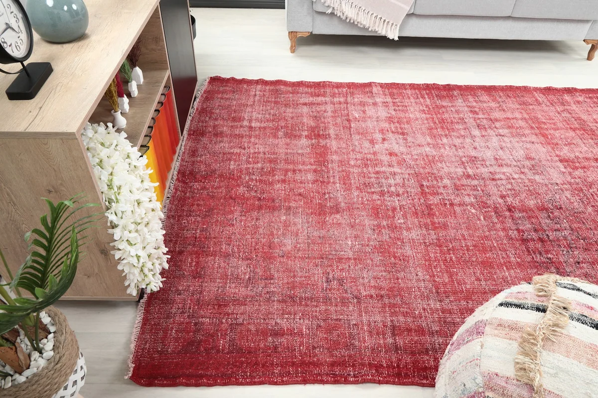 Red distressed vintage rug in a living space, seen from another angle, complementing the decor.