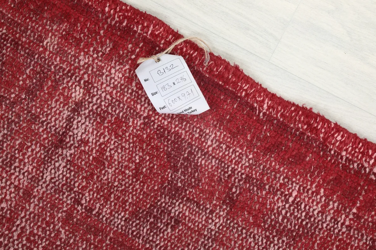 Close-up detail of the rug's tag, indicating origin and material on the vintage hand-knotted piece.