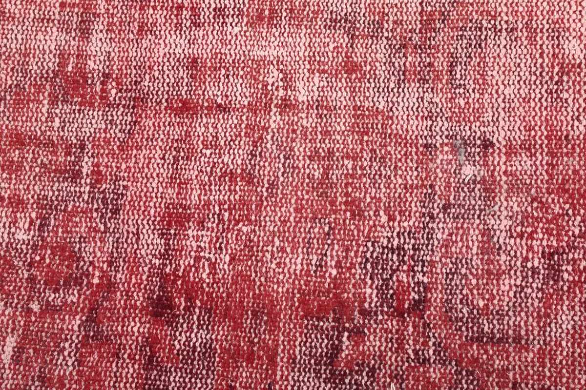 Close-up of the low pile and distressed texture of the red vintage hand-knotted wool rug.