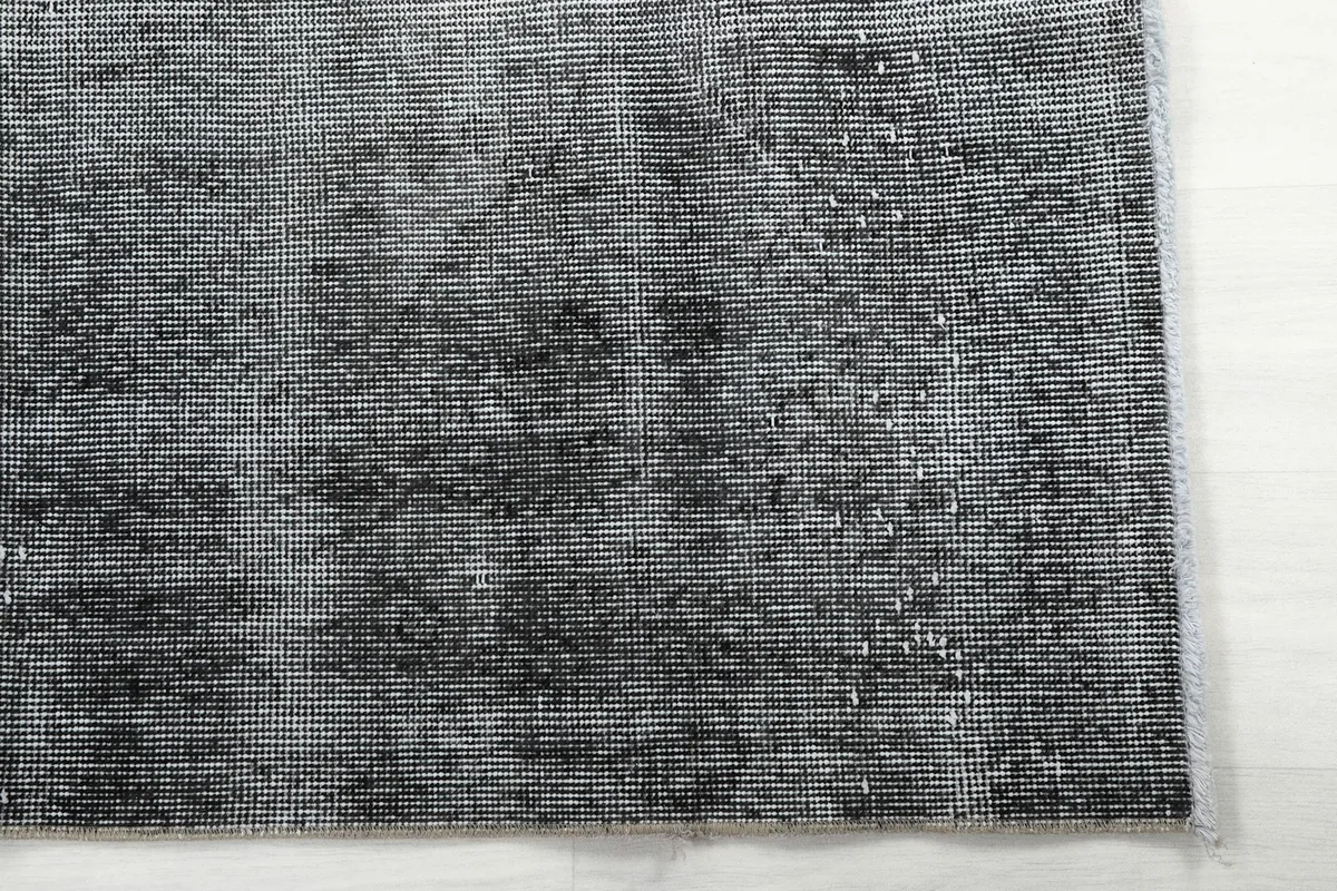 Corner detail of the rug, highlighting the subtle variations in its charcoal and gray coloring.