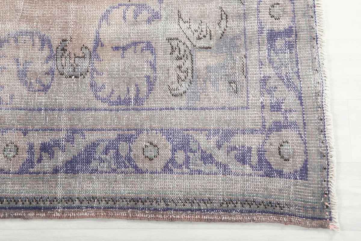 Detail of the rug's border with faded purple geometric patterns