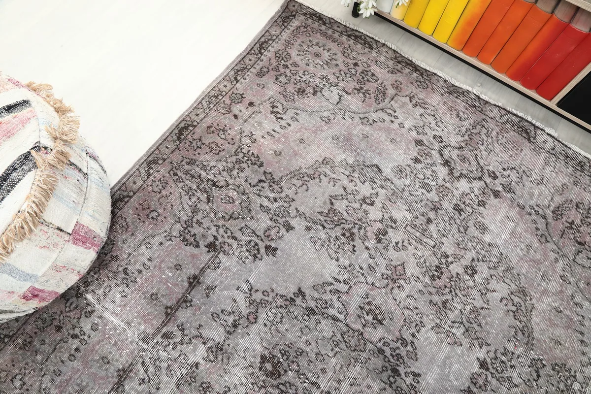 Top-down angle showcasing the rug's overall pattern, including the border and field, next to a pouf.