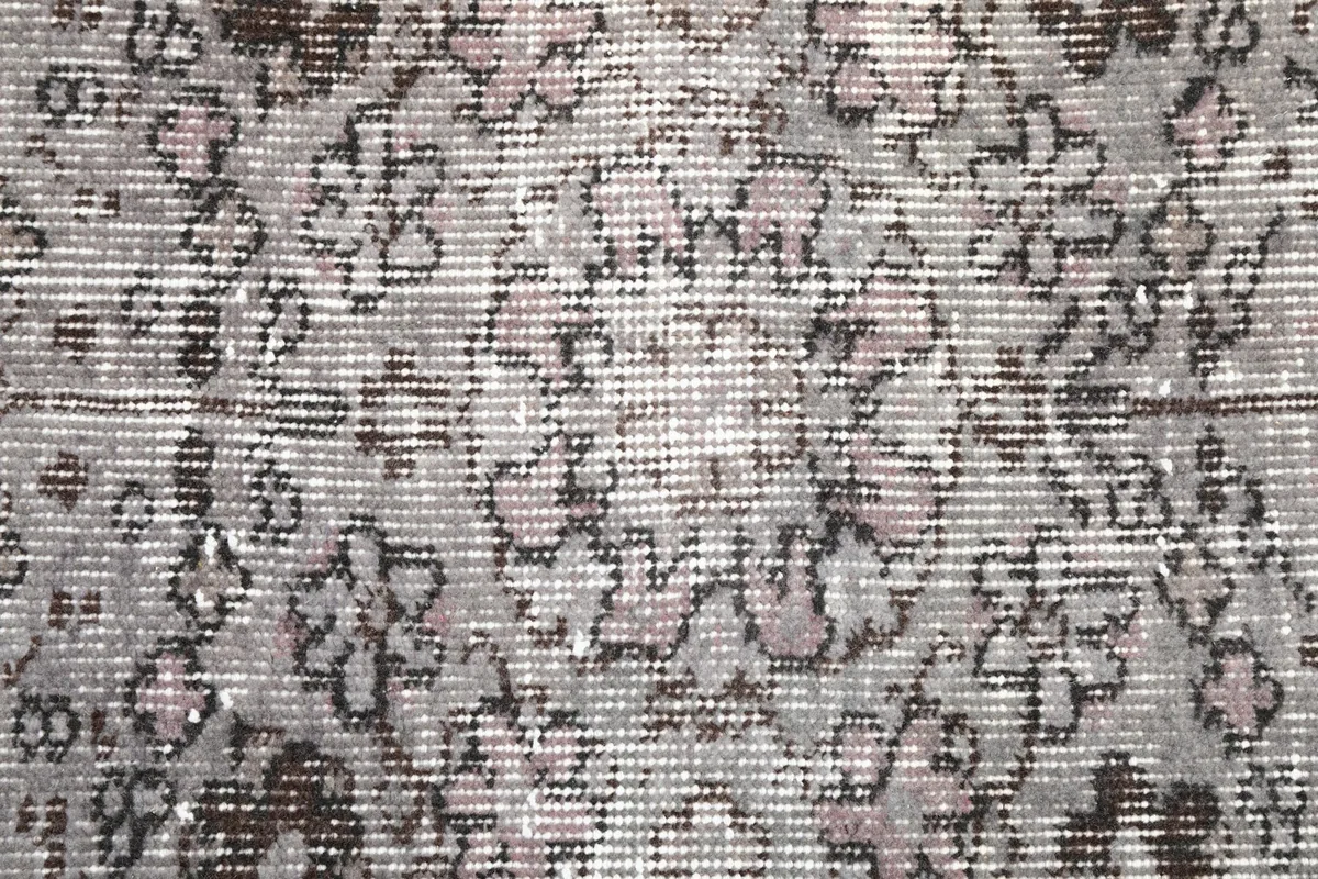 Close-up of the low wool pile, revealing the hand-knotted texture and faded gray and rose colors.