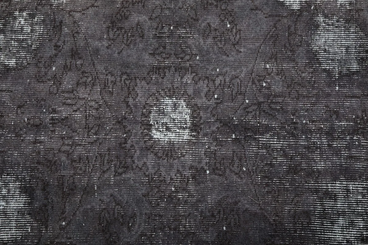 Close-up of a central medallion motif with visible wear and color variations on the charcoal field