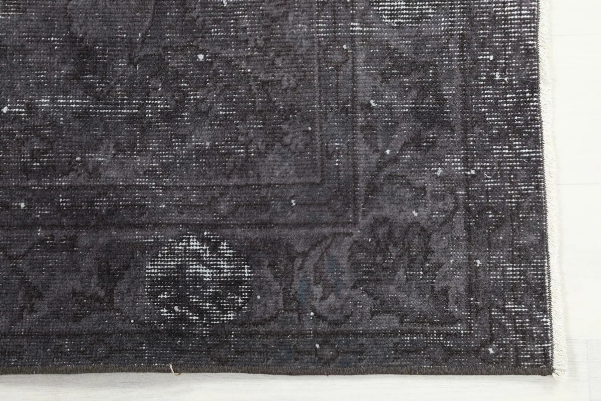 Detail of the rug's border design and corner, highlighting the intricate faded patterns