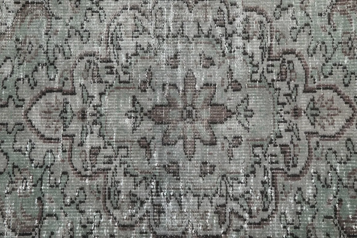 Close-up of the rug's central medallion, revealing the hand-knotted wool and subtle green hues