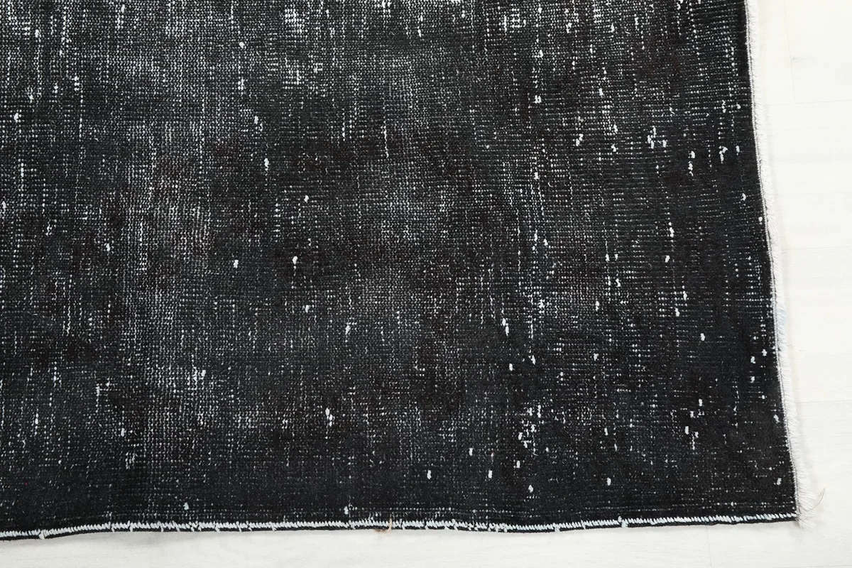 Corner detail of the charcoal rug, showing the distressed pile and edge finishing