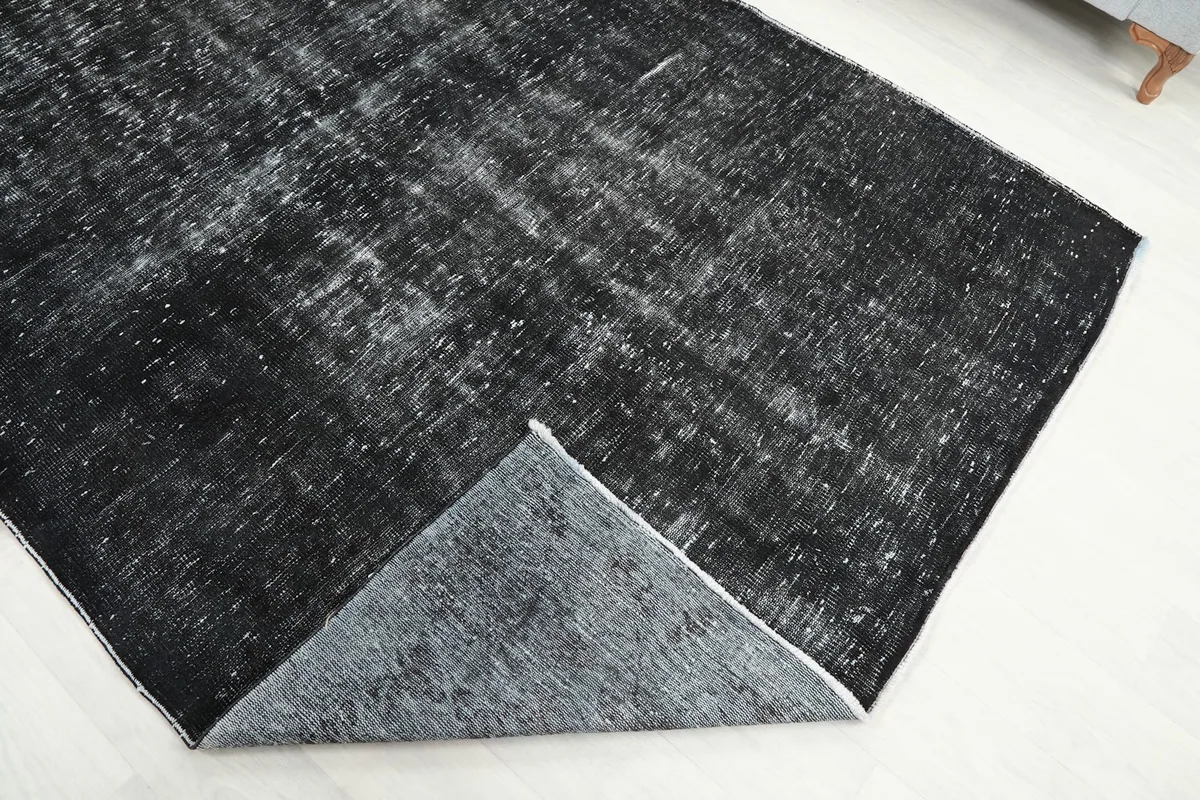 Corner lifted, revealing the back of the hand-knotted wool rug and cotton foundation