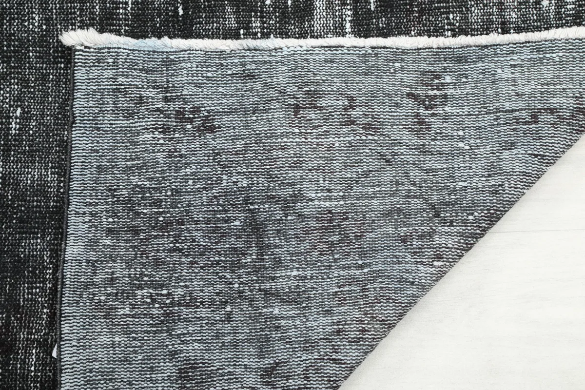 Close-up of the rug's reverse side, showing the hand-knotted construction and fringe