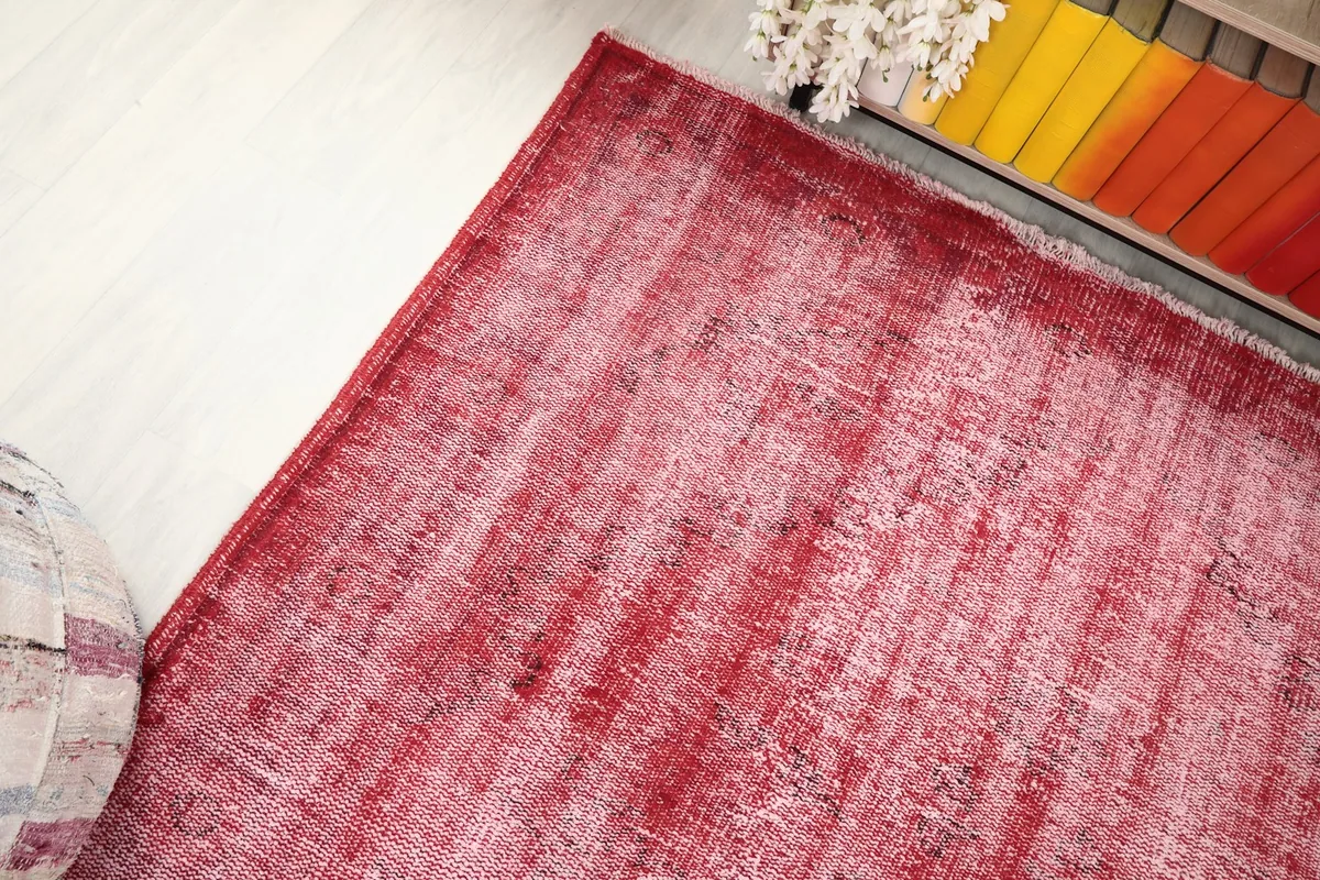Corner angle of the red distressed rug, showing its texture and how it complements the surrounding decor.