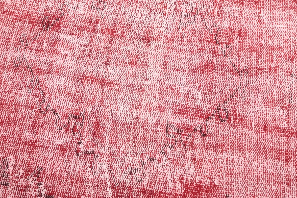 Close-up detail of the rug's surface, showcasing the low pile and the blend of red, rose, and ivory fibers.