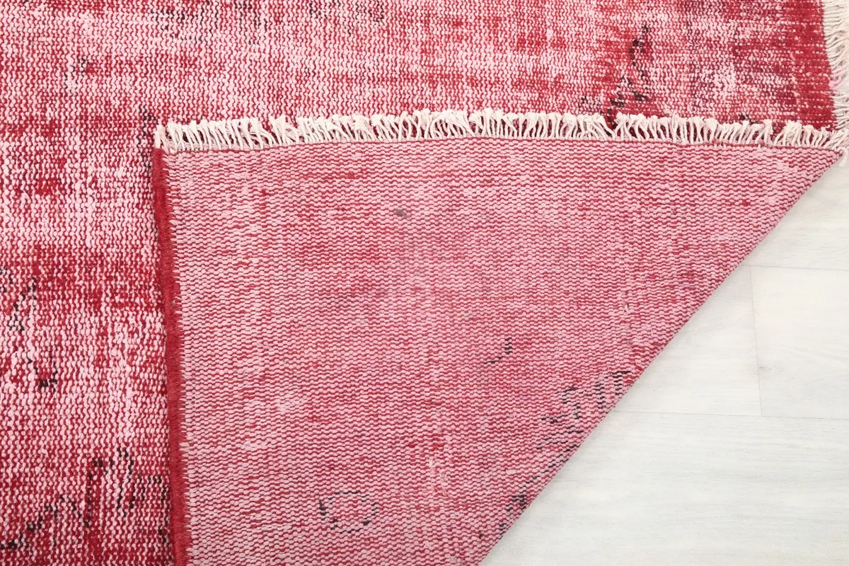 Detail of the rug's back, showing the tight knotting of the cotton foundation and the fringed edge.