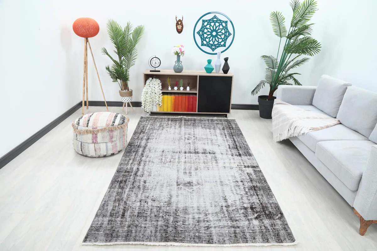 Vintage Anatolian rug with charcoal and ivory tones in a modern living room setting with a light sofa.