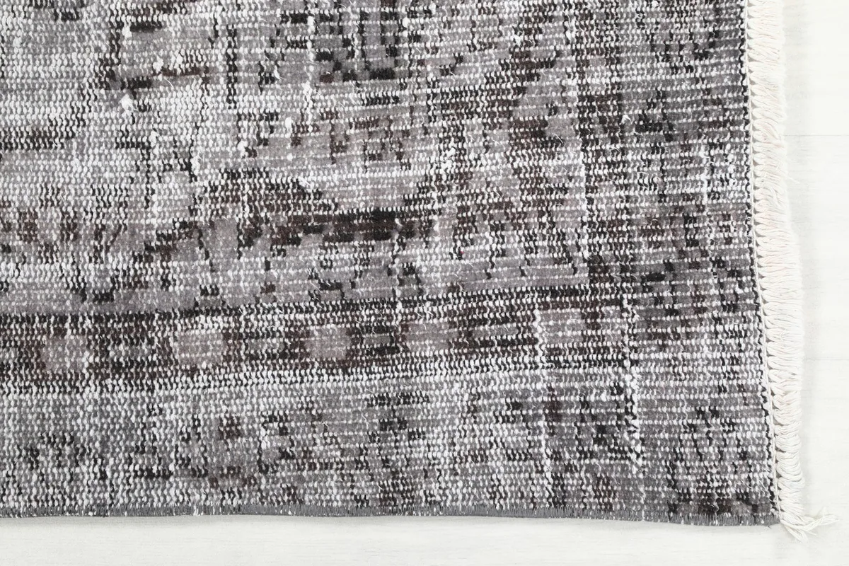 Detailed view of the rug's edge, showing the hand-knotted wool pile and cotton foundation.