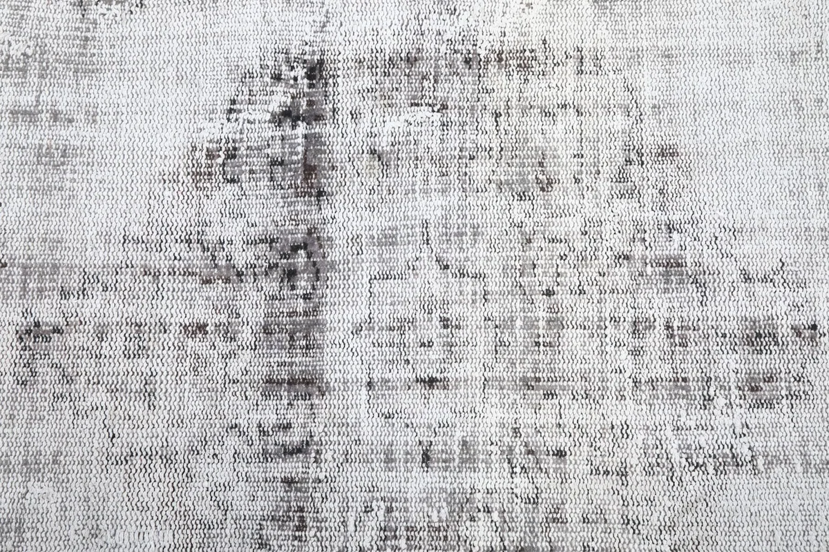Close-up of the central field of the rug, revealing the subtle patterns and worn texture.