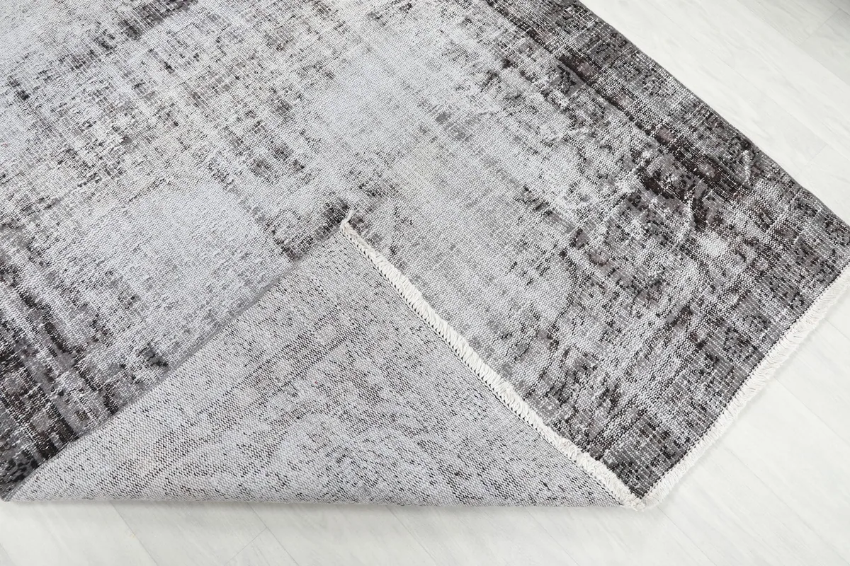 Folded corner of the rug, showing the reverse side with its cotton foundation and knotting detail.