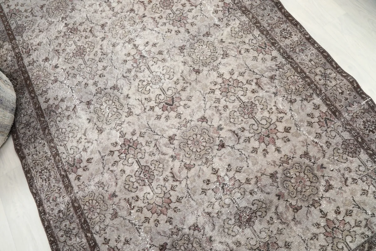 Detailed angle view showcasing the aged patina and intricate floral motifs of the rug